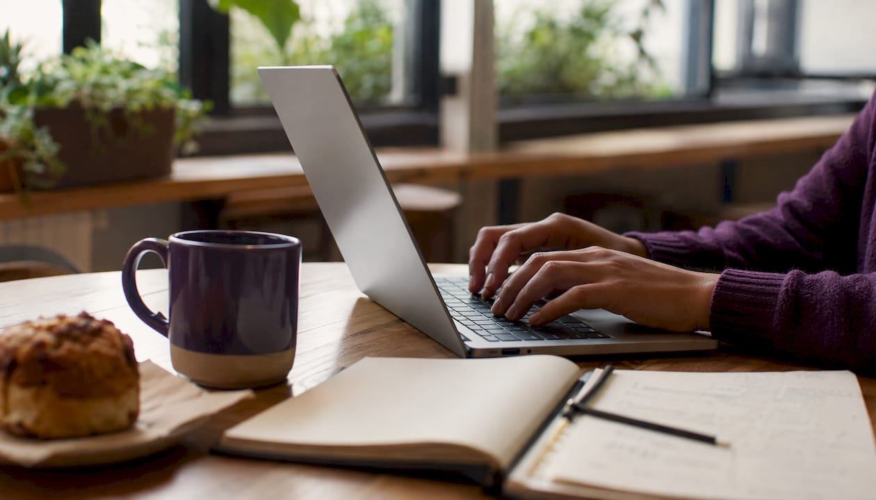 Close-up of hands typing CRM workflow on laptop