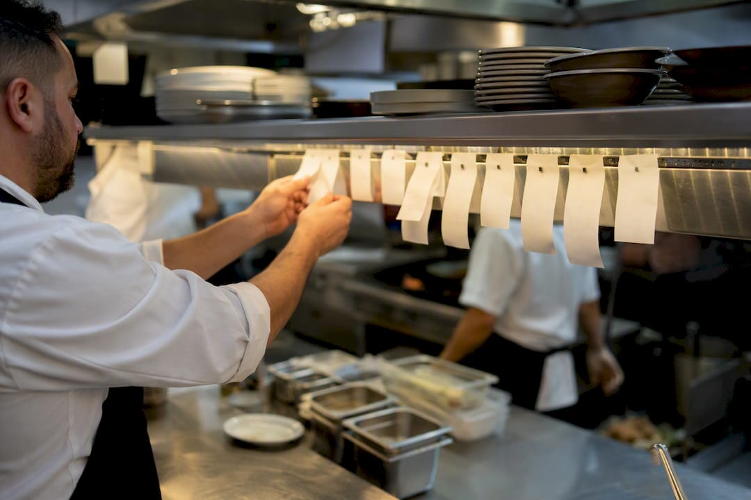 Chef handling printed kitchen orders