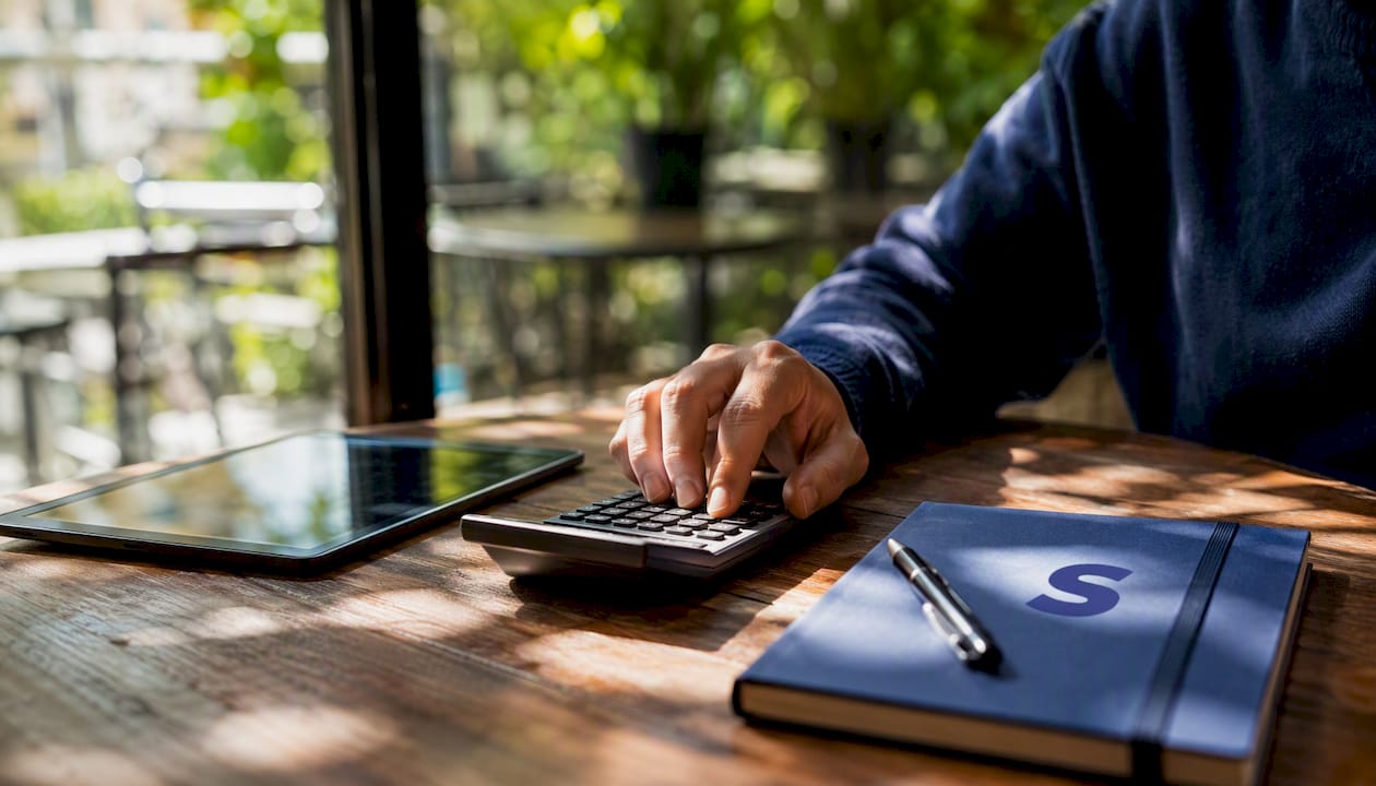Hands calculating ROAS with tablet and calculator