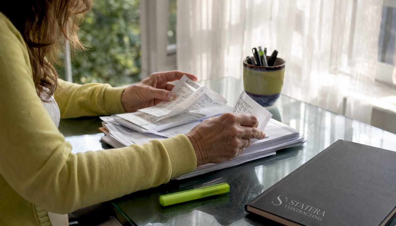 Hands organizing renovation invoices for tax credit claim