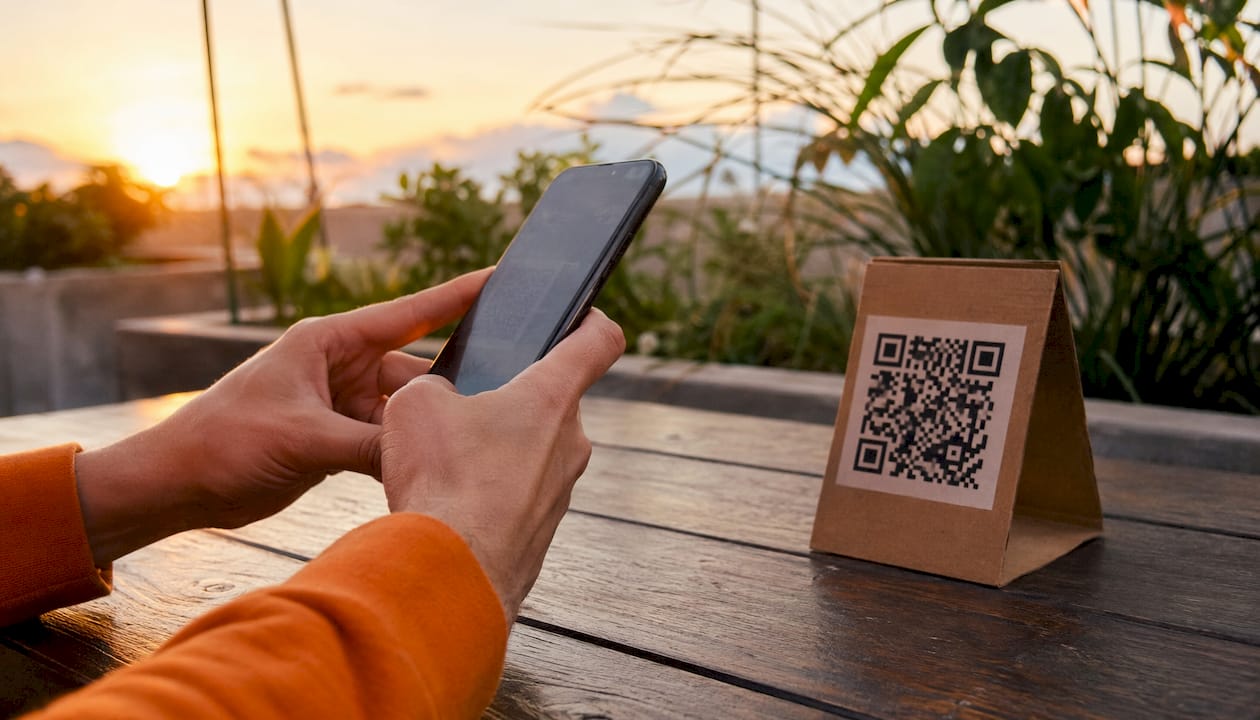 Una persona sostiene su móvil y escanea un código QR con la cámara.