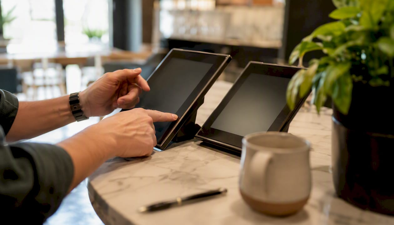 Manos actualizando los dispositivos de menú digital en un restaurante