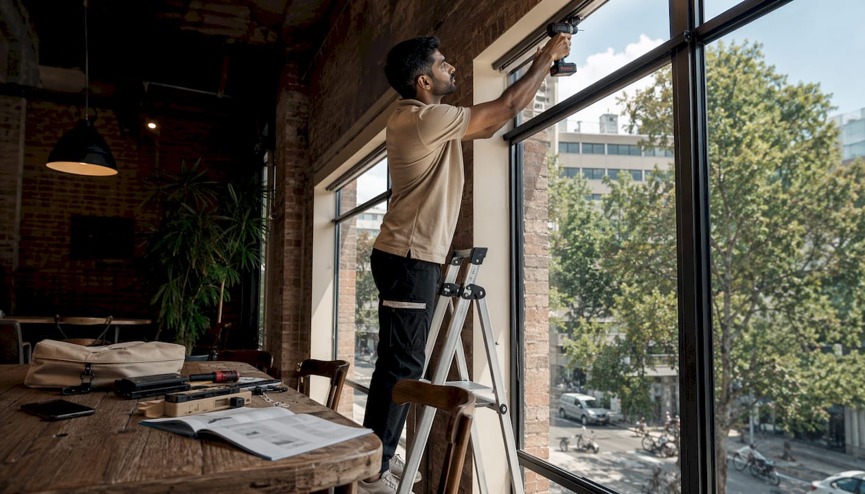 Technician fitting motorized smart blinds in apartment