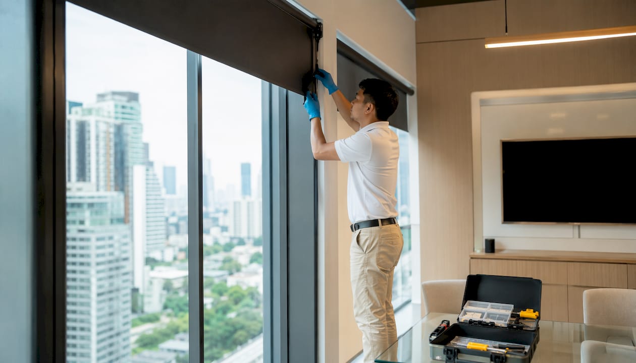 Technician installing commercial-grade blind hardware