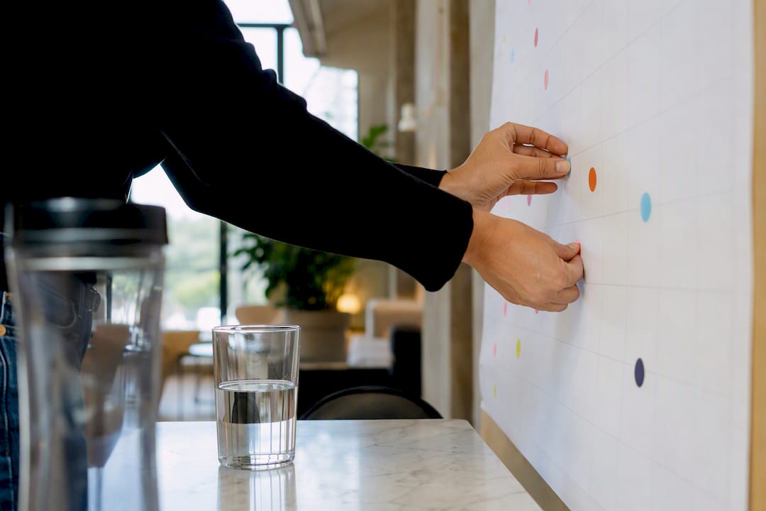 Hands adjusting sticky dots for validation on wall chart