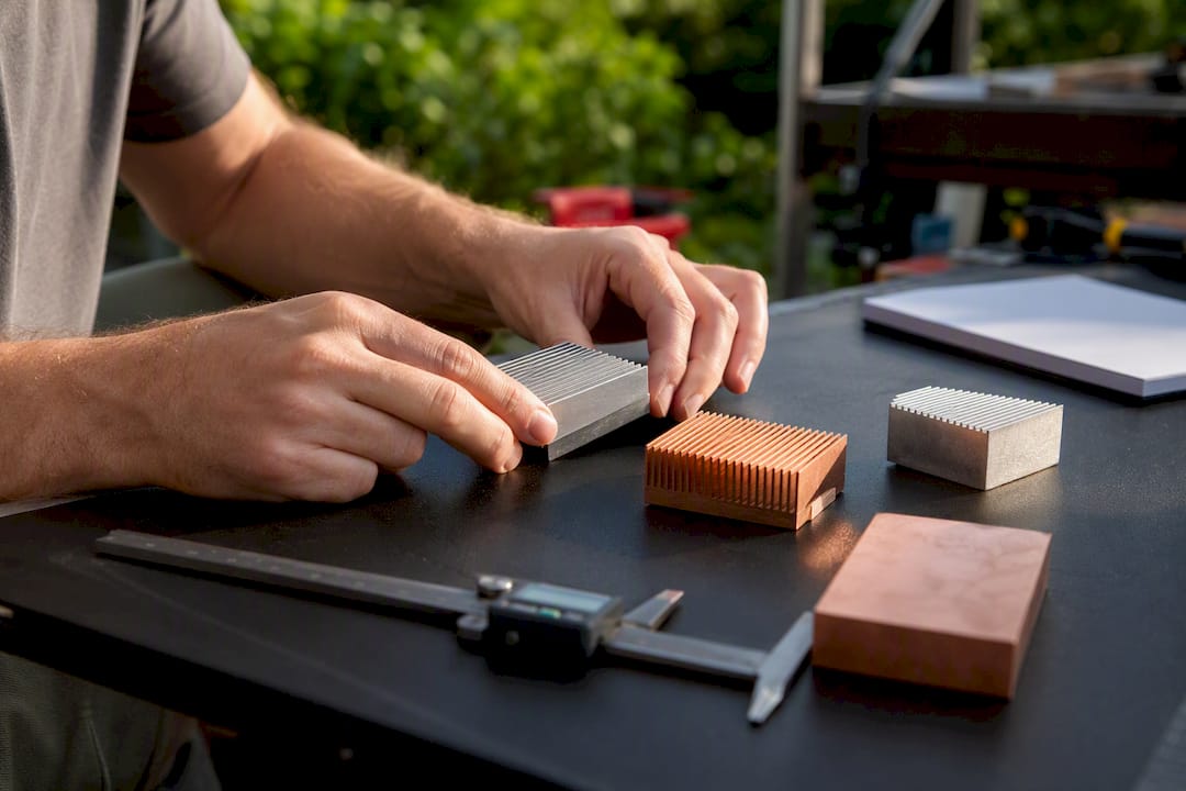 Hands comparing aluminum and copper heat sink samples