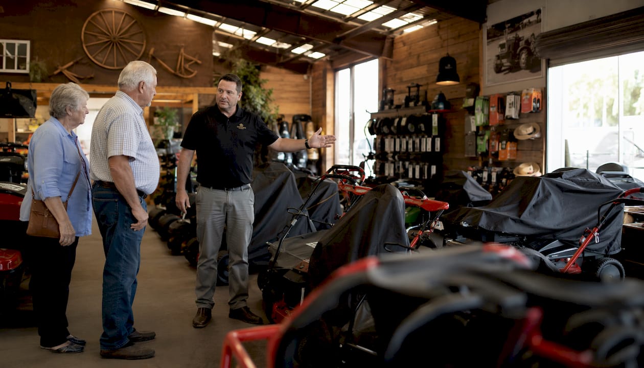 Dealer showing lawn mower alternatives to couple