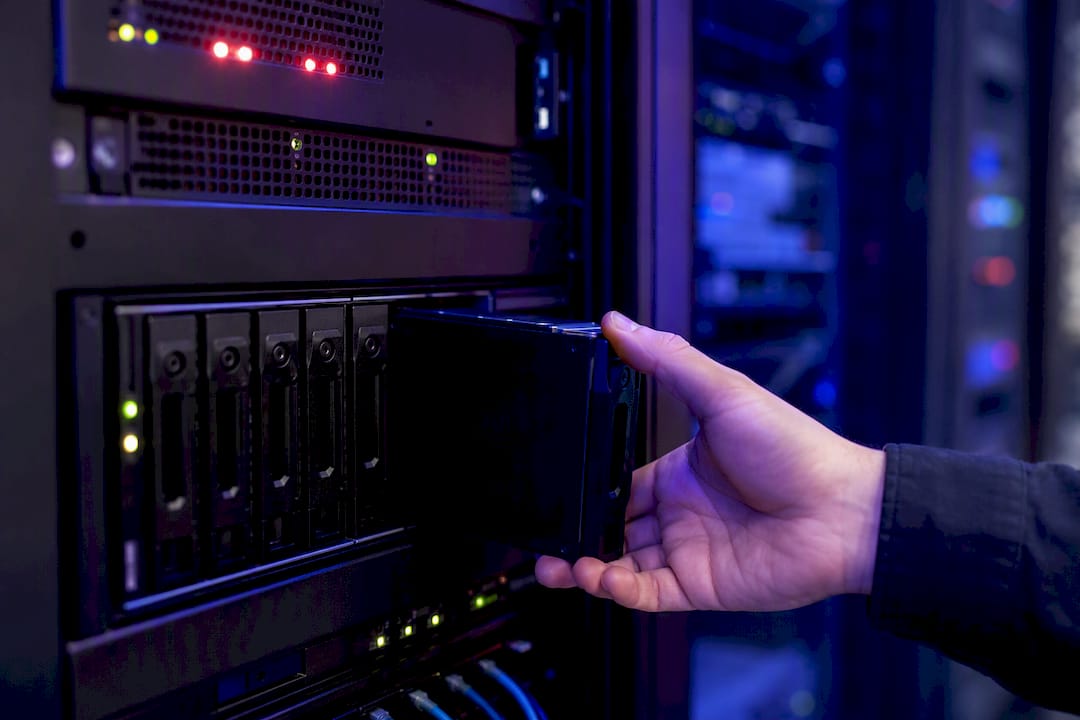 Mani che estraggono un disco di backup all'interno della sala server