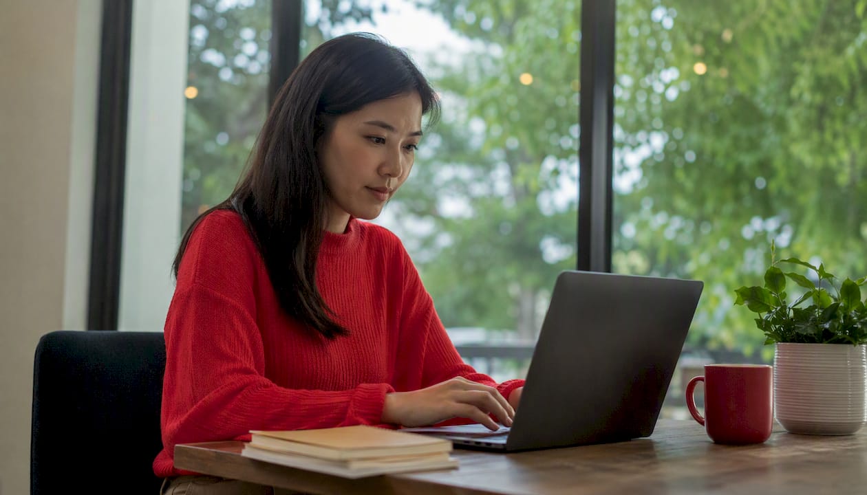 Hands typing email logs on laptop in home office