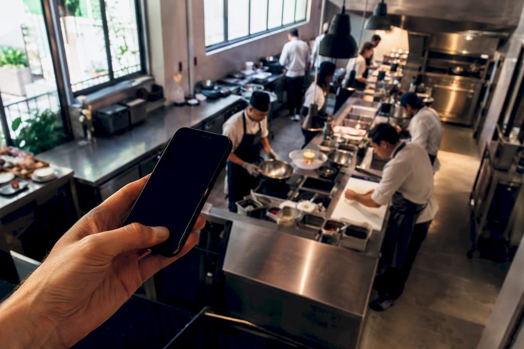 Hand sending SMS in restaurant kitchen