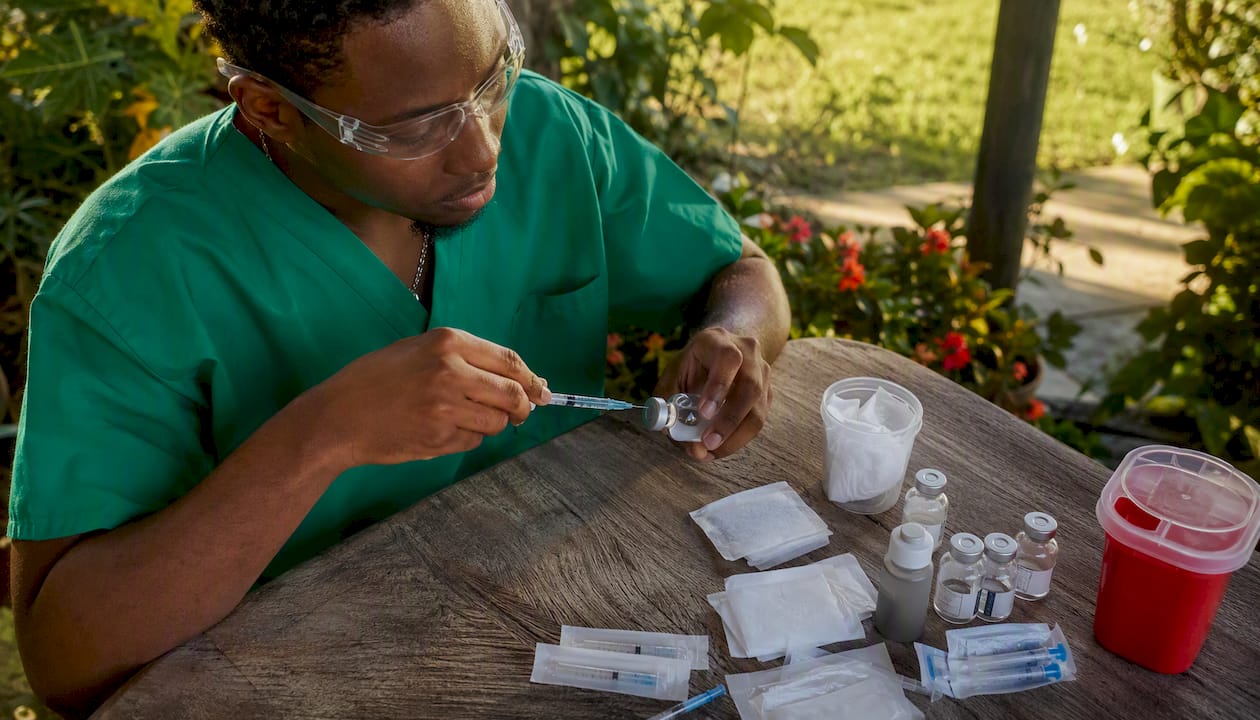 Lab technician drawing sterile water with syringe