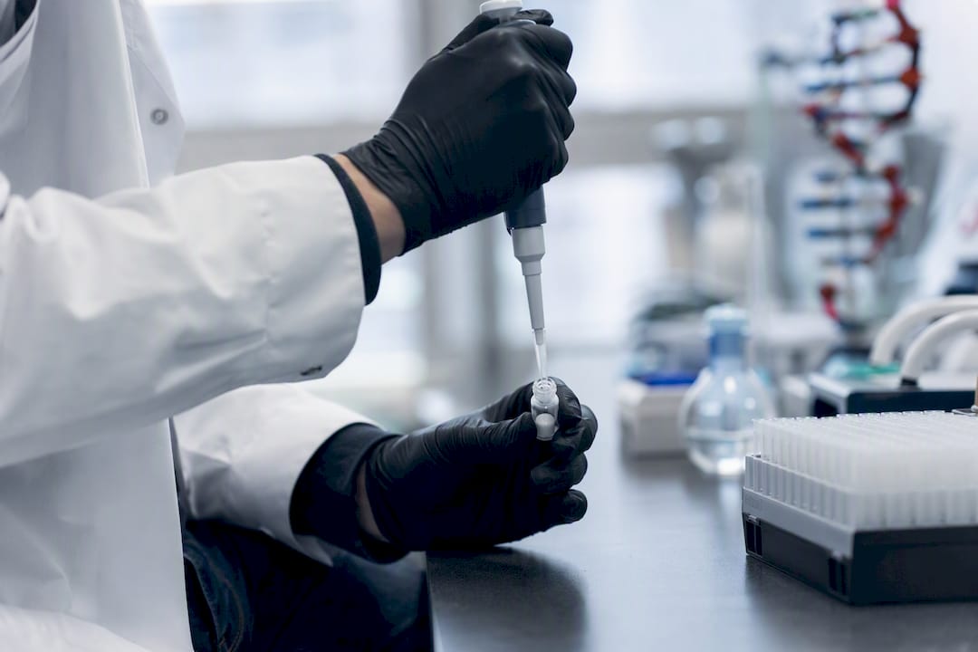 Hand pipetting solvent into peptide vial for reconstitution