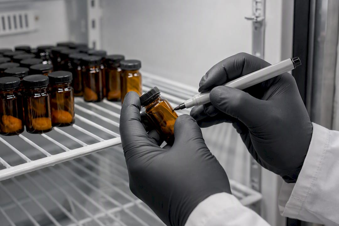 Gloved hands labeling peptide vials in lab fridge