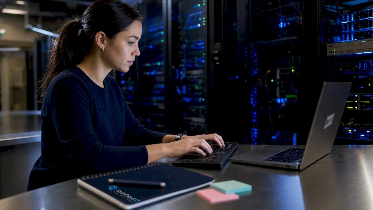 Close-up hands typing in server room environment