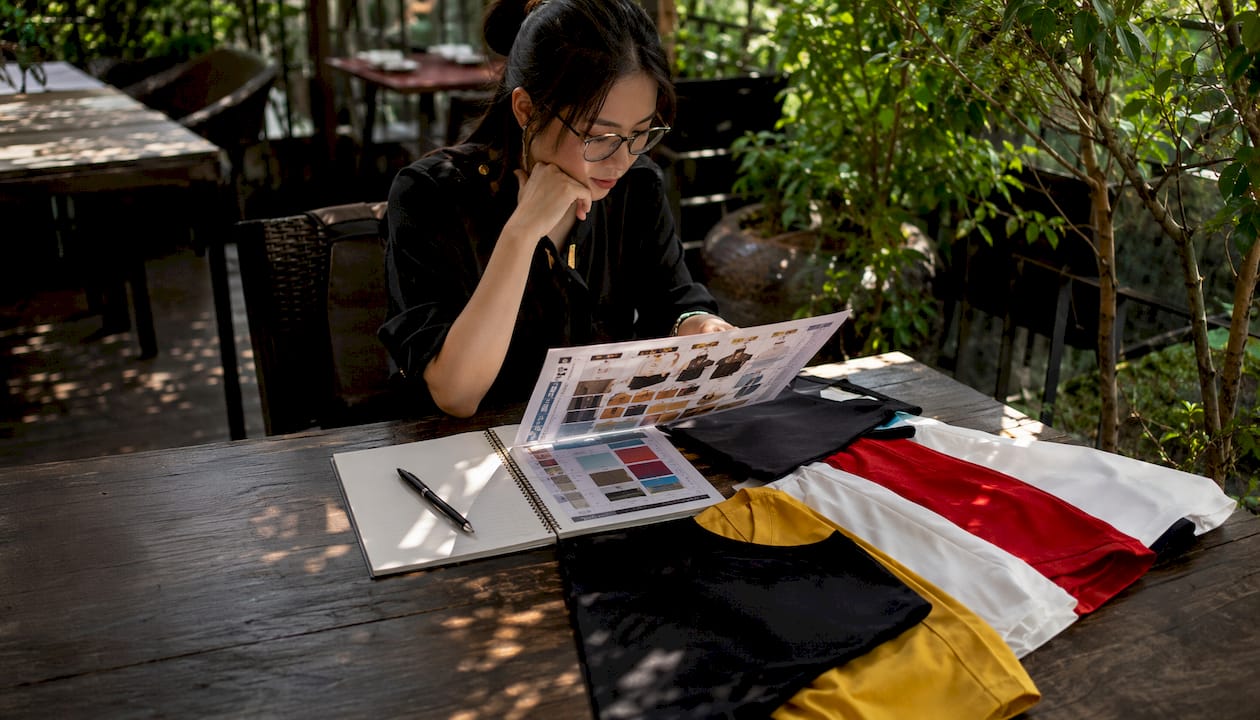 Designer reviewing t-shirt printing cost comparison sheets