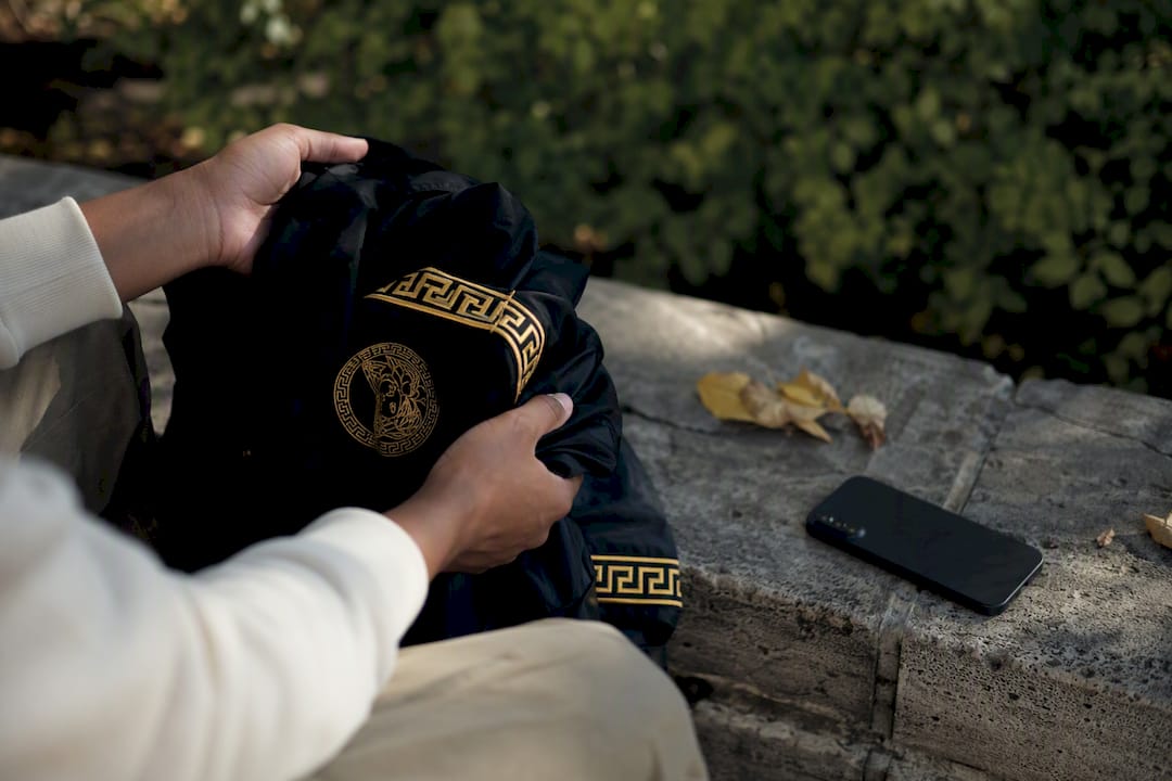 Hands holding folded black streetwear jacket
