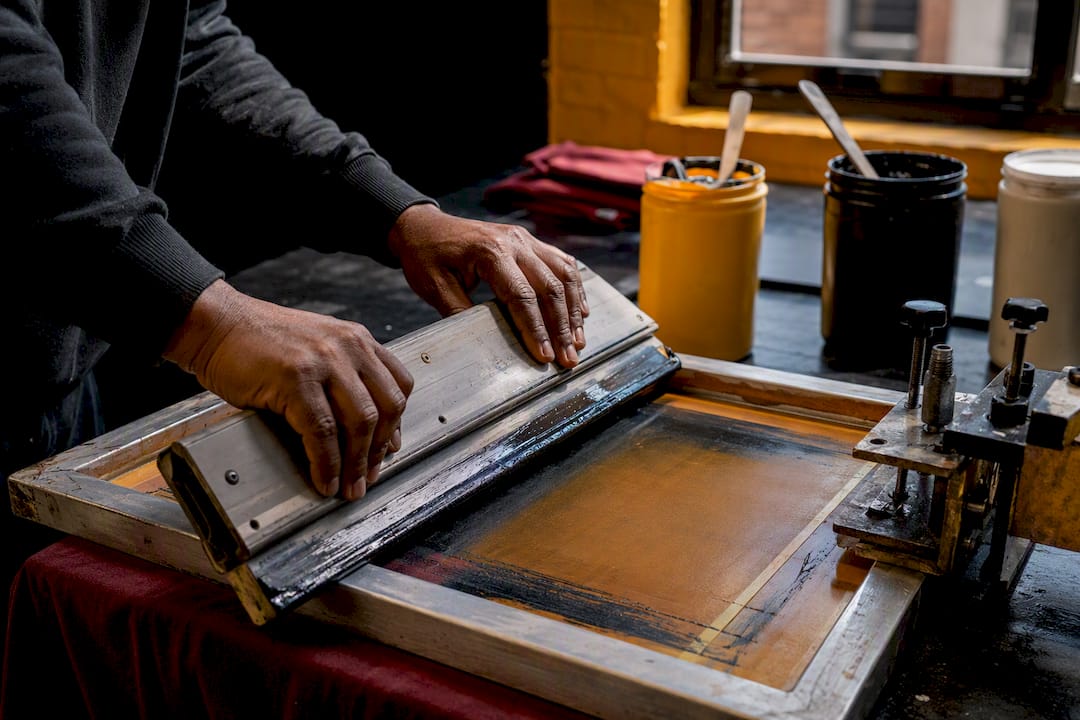 Hands screen printing a small garment batch
