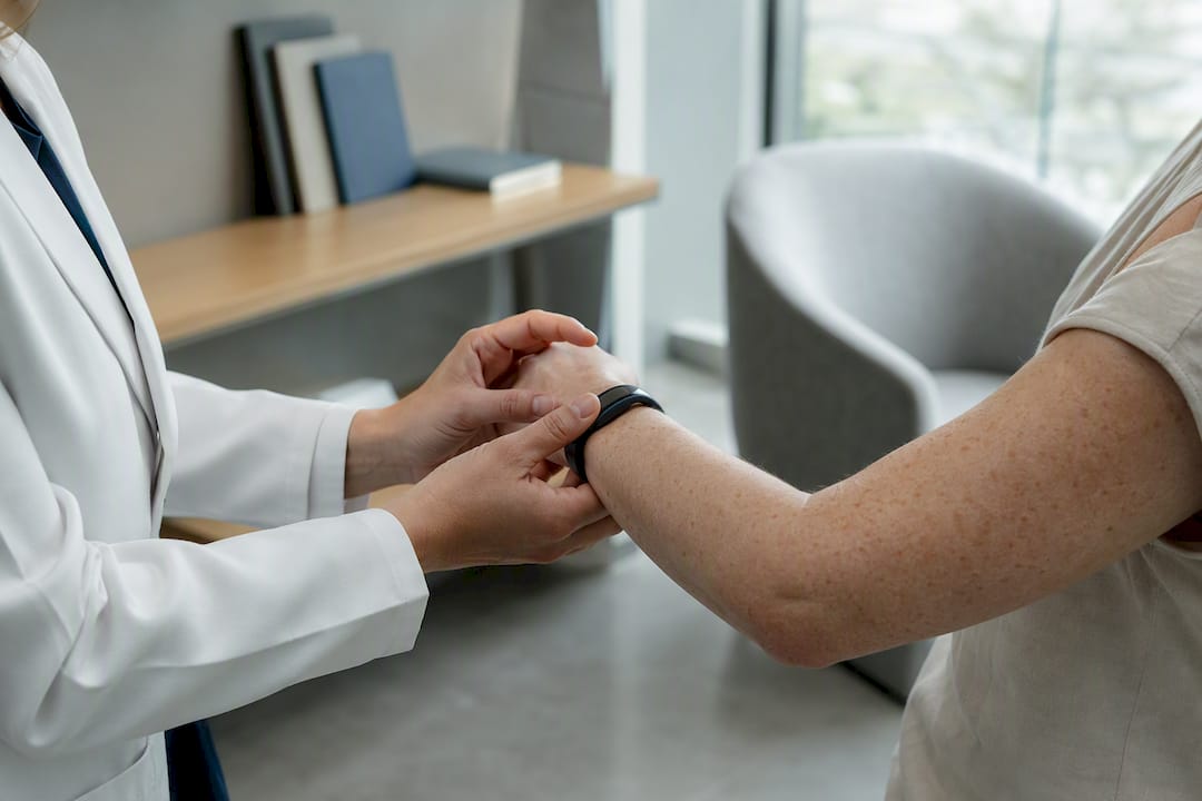 Hands adjusting health wearable on wrist in clinic