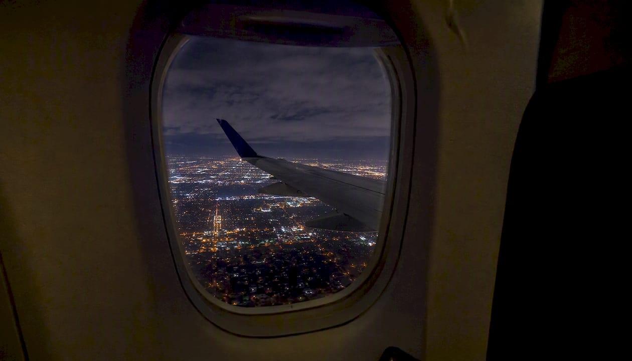 Night flight wing over illuminated cityscape