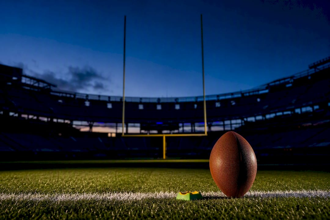 Football beneath stadium goalposts at dusk