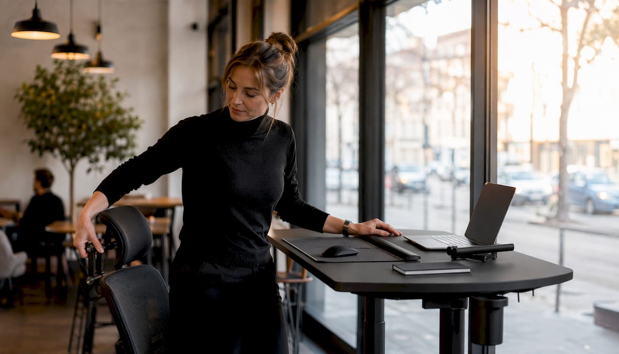 Im Homeoffice stellt eine Frau ihren Bürostuhl optimal ein, um bequem und rückenschonend zu arbeiten.