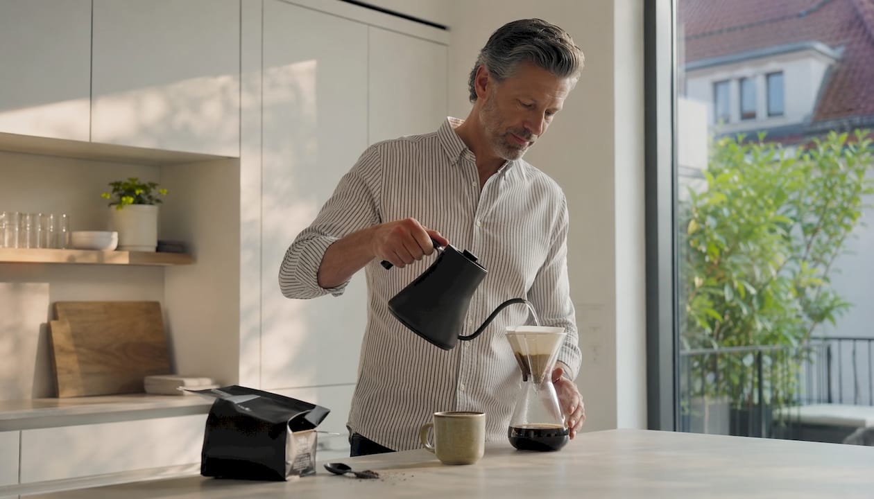 Un homme prépare son café du matin dans sa cuisine confortable.