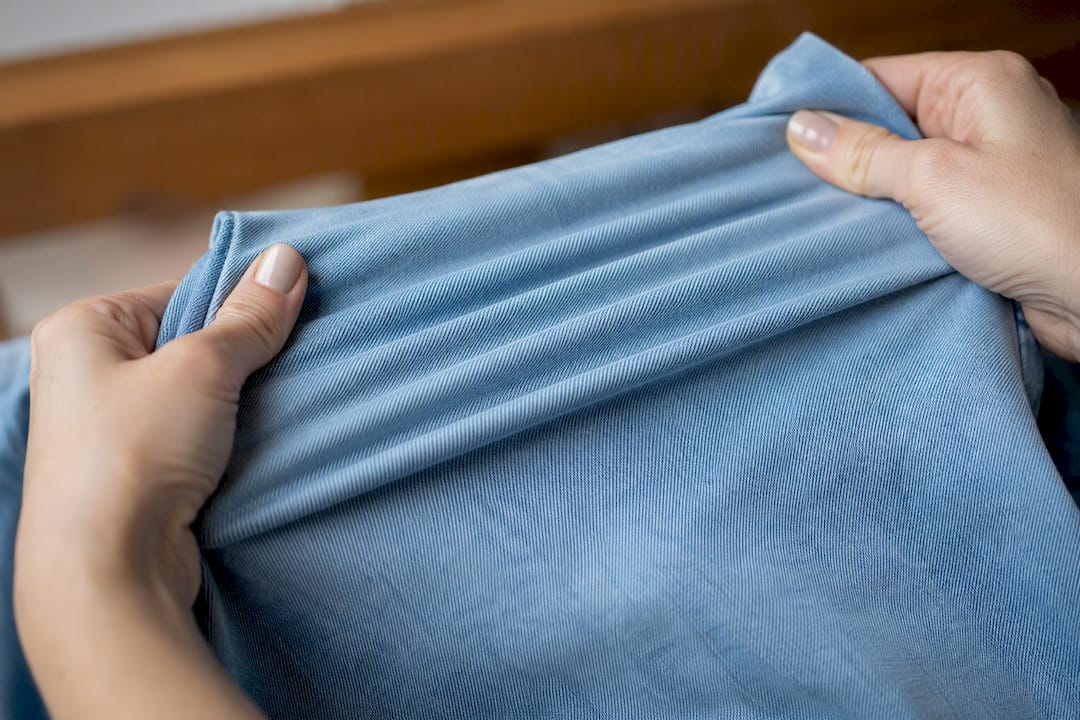 Hände, die den Denim-Stoff dehnen