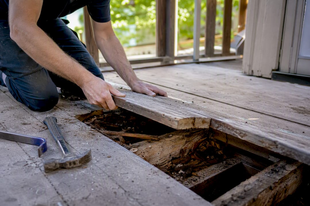 Hands inspecting hidden floor rot pre-renovation