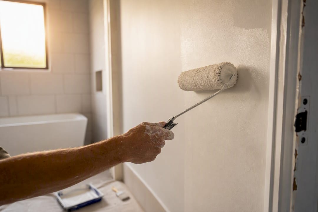 Painter applying satin paint in bathroom