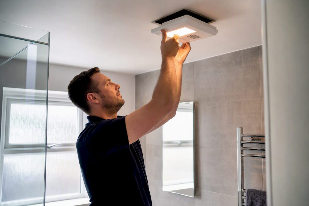 Hands installing bathroom light and extractor fan