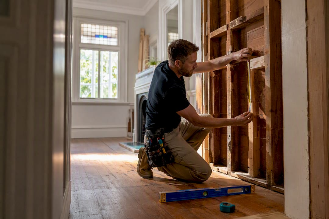 Builder measuring exposed villa wall framing