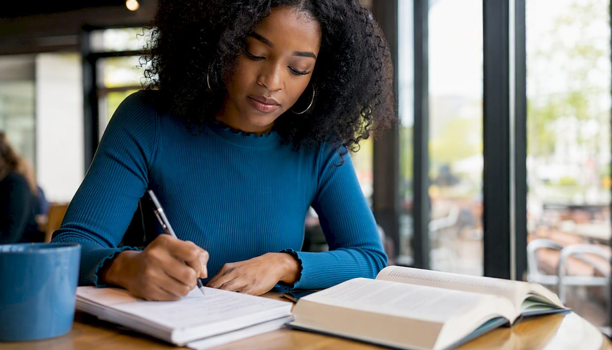 Hands taking notes from communication book at library