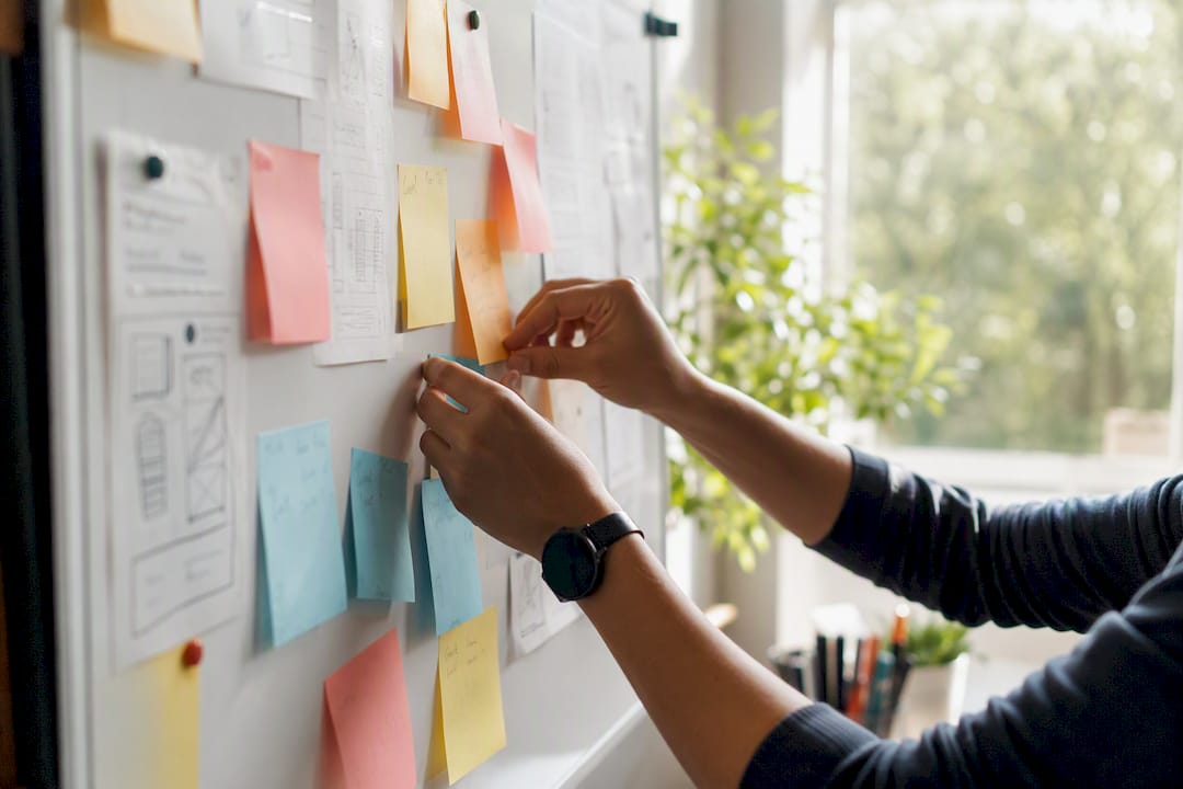 Hands adding sticky notes on campaign board