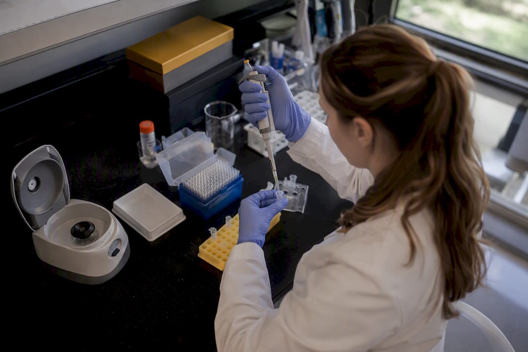 Hands pipetting liquids in cancer research lab