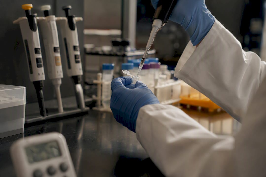 Hands pipetting molecular glue reagent in lab