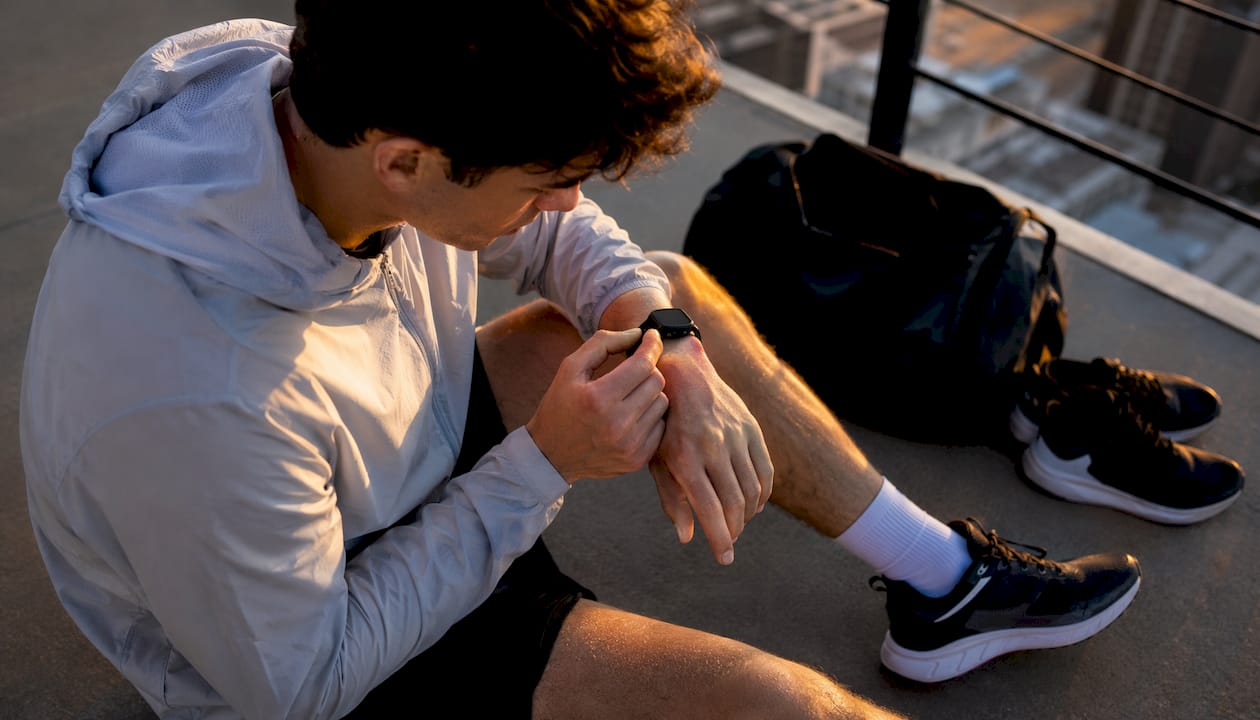 Man adjusting silicone watch on irritated wrist outdoors