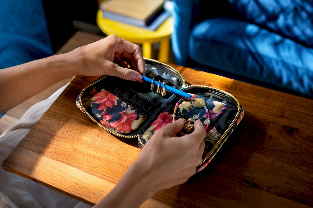 Hands using household items for jewelry packing hacks