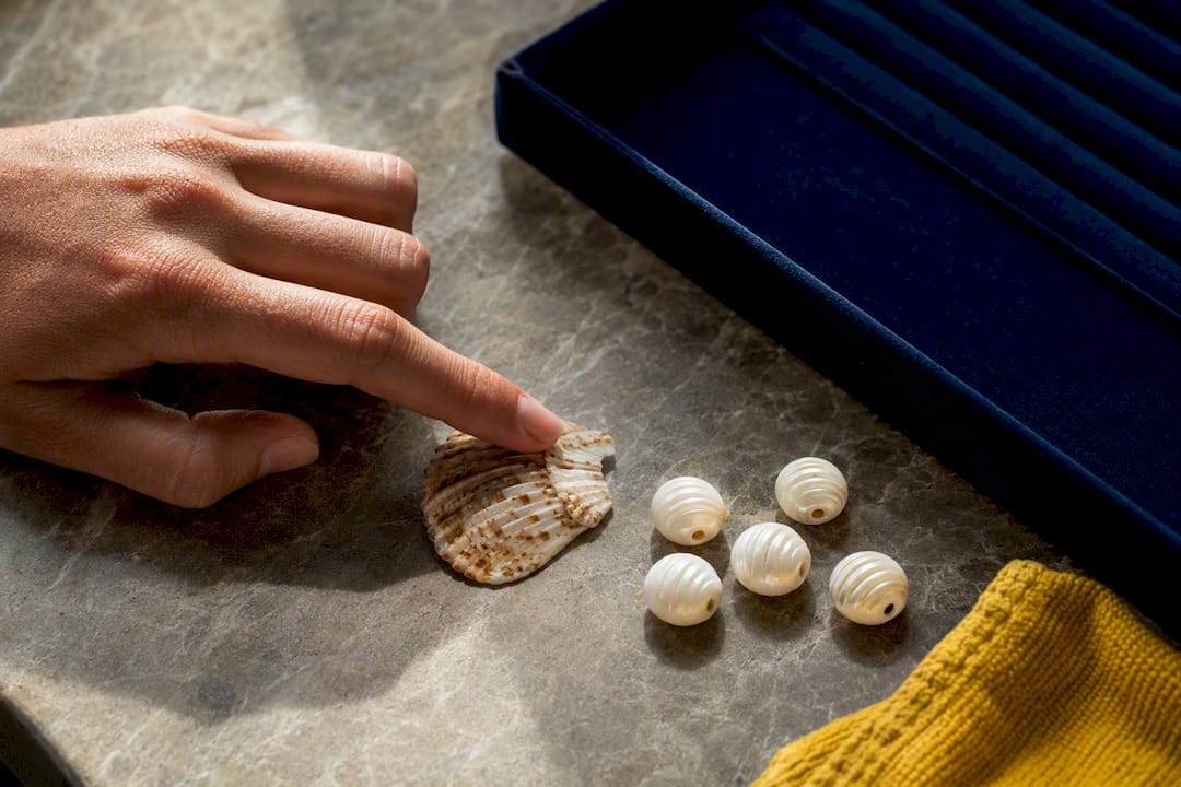 Hand comparing natural shell and imitation beads