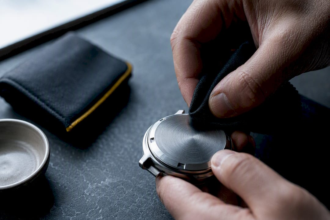 Soft cloth cleaning an engraved watch caseback