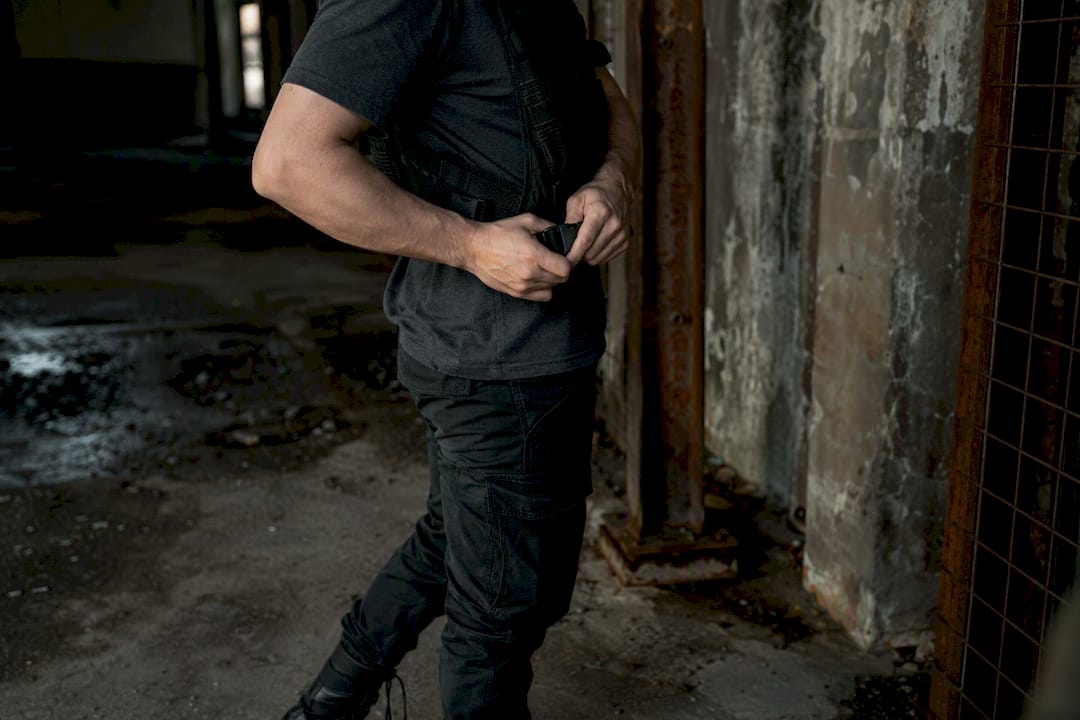 Adjusting utility vest over black streetwear outfit