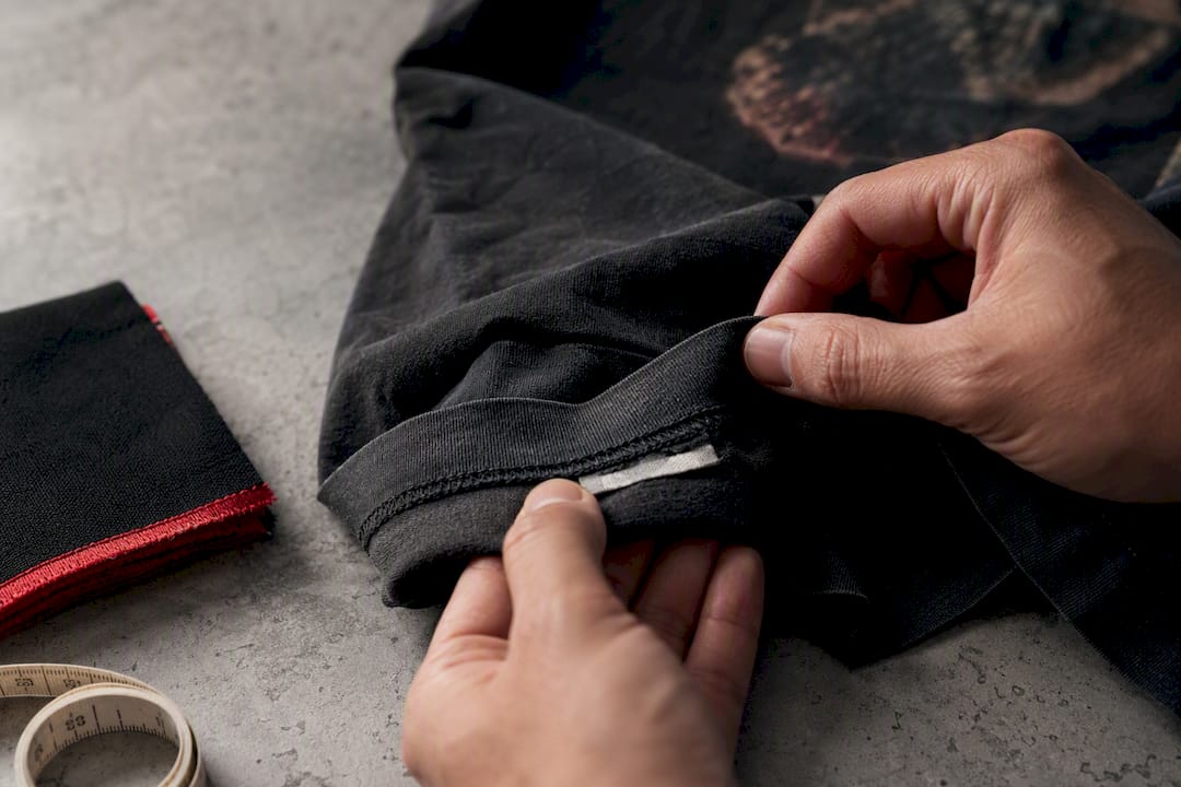 Hands inspecting vintage tee stitching