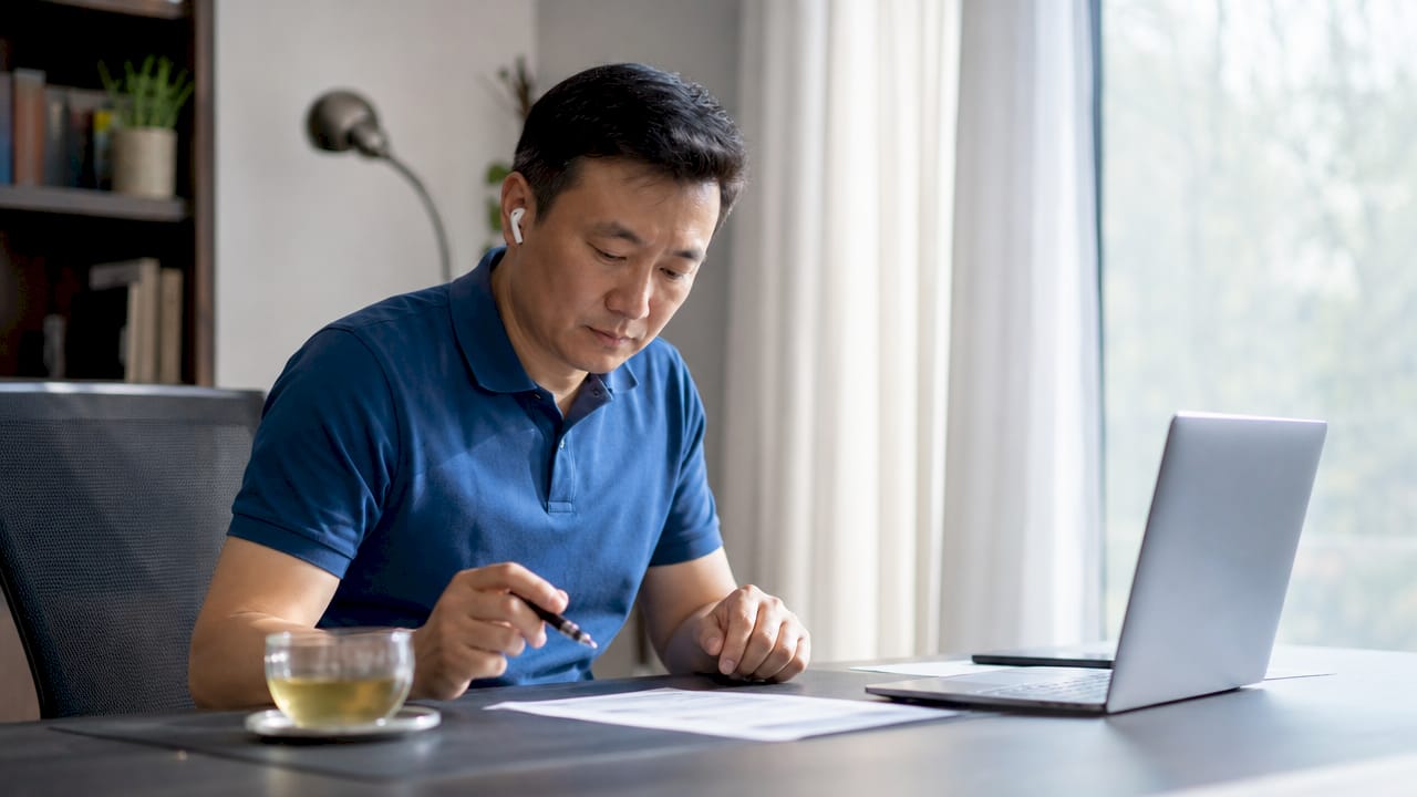 Parent listening to podcast and reviewing notes at kitchen table