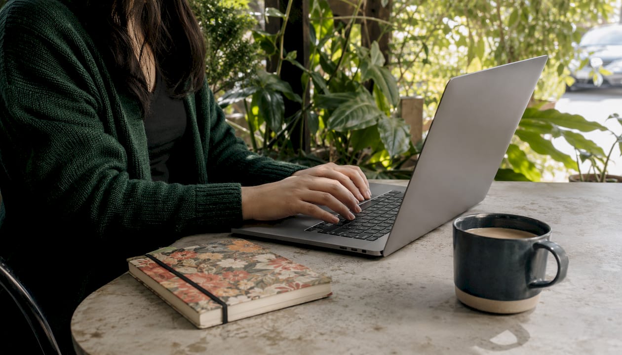 Hands typing on laptop in home office