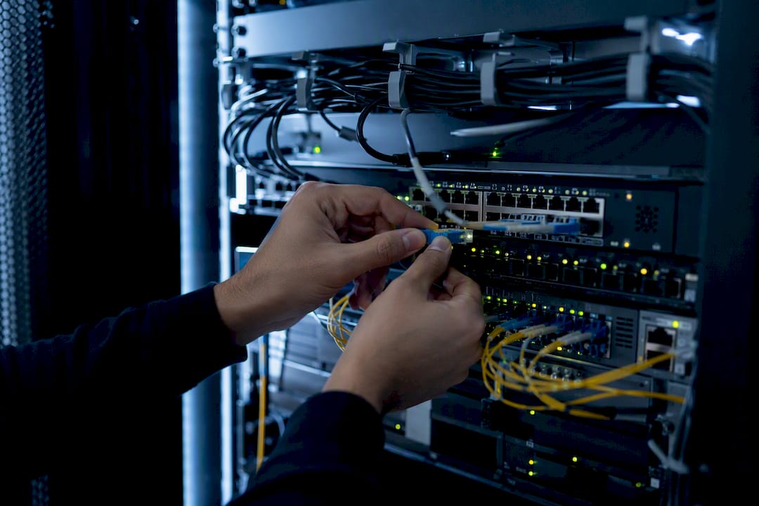 Hands connecting fiber cable to network switch