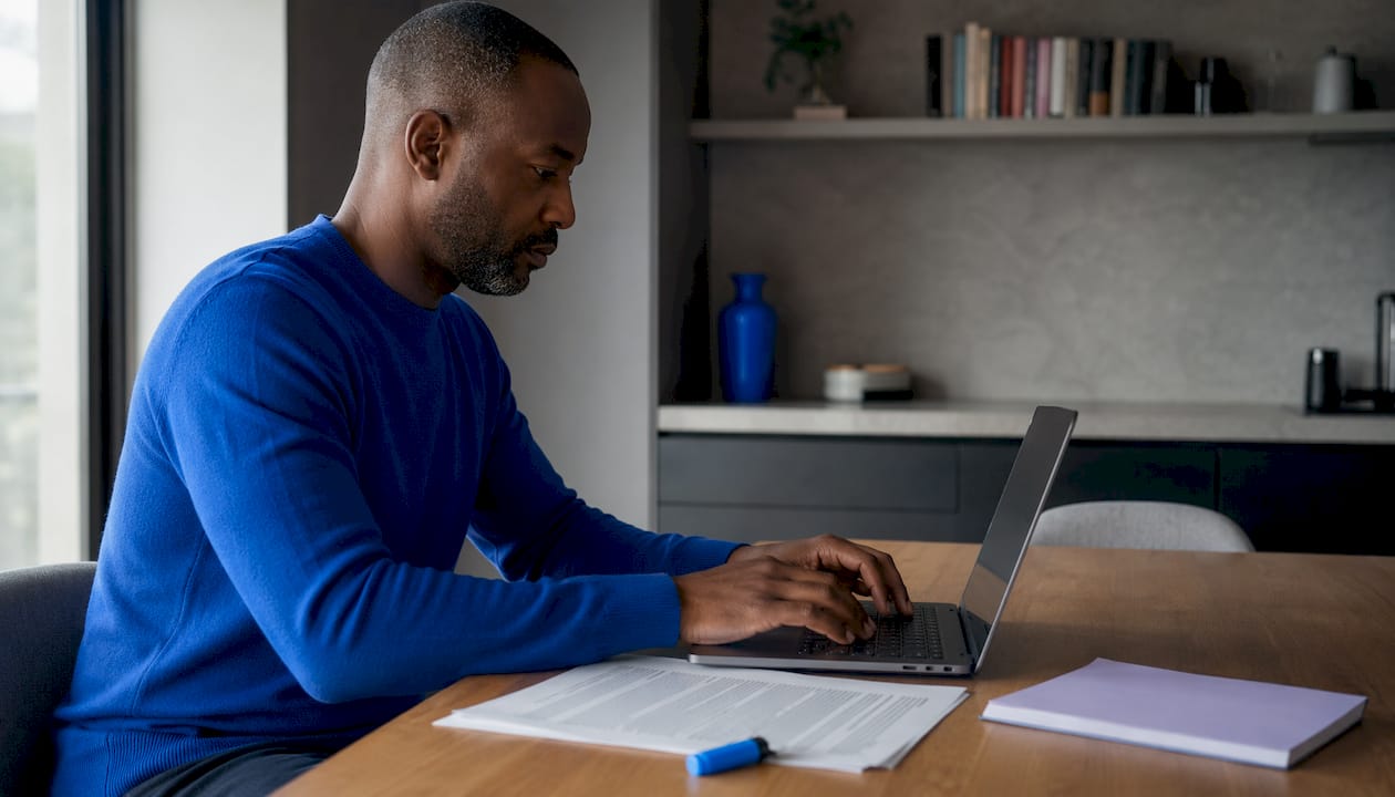Over-shoulder view of man drafting NDA template at home