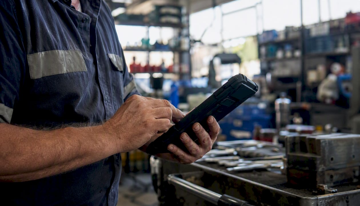 Technician holding rugged device in workshop