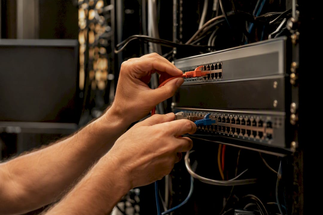 Hands connecting network cables in dealership server rack