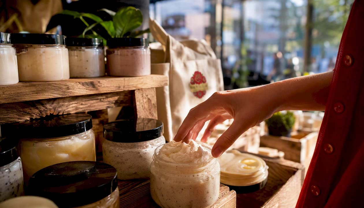 Hand selecting natural skincare product from shelf