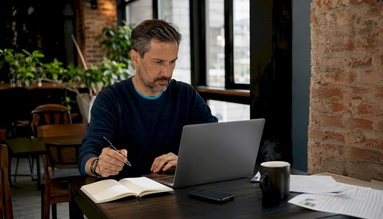 Un consultant en pleine réflexion devant son ordinateur portable, installé à son bureau.