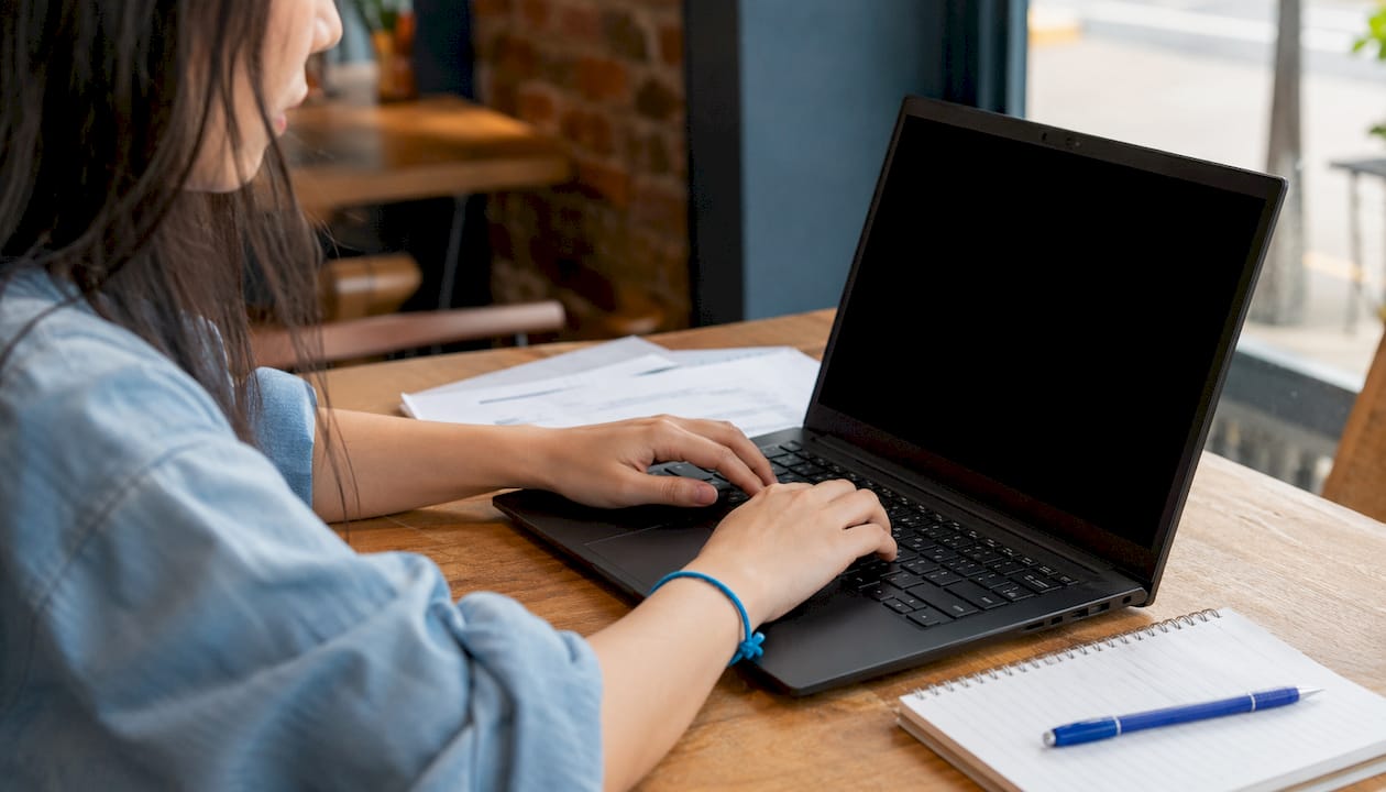 Une femme tape sur son clavier, installée dans un bureau lumineux.